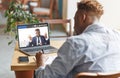 Guy attending online training with business coach, listening, taking notes