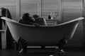 Guy in bathroom with toiletries and chair on background. Sexuality and relaxation concept: macho lying naked in bathtub