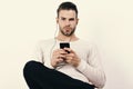 Guy with beard holds MP3 player and wears earphones on white background. Macho with headphones and cell phone listens to Royalty Free Stock Photo