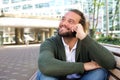 Guy with beard sitting on bench in the city with mobile phone Royalty Free Stock Photo