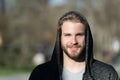 Guy with beard smile in hood on sunny day. Bearded man wear casual sweatshirt outdoor. Fashion macho smiling in stylish sportswear Royalty Free Stock Photo