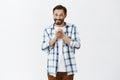 Guy begging for favor, being grateful for help, standing with tight and hopeful smile over gray background in checked