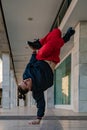 A guy in a black sweatshirt and red pants breakdancing on a sidewalk. Space to write Royalty Free Stock Photo