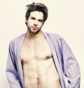 Guy in blue bathrobe with torso and six packs. Sportsman with muscular body in home or bath clothes. Royalty Free Stock Photo
