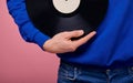 Guy in a blue sweater and denim pants on the background holds a black vinyl record in his hand Royalty Free Stock Photo