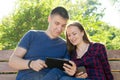 Guy in blue t-shirt and girl in plaid shirt solve problems on the tablet