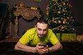 A guy in a bright green T-shirt is lying on the carpet with a mobile phone in his hands. Communicate on a smartphone against the Royalty Free Stock Photo