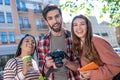 Guy with camera, two girls with coffee and tablet, happy