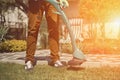 Guy in casual clothes and colorful gloves is cutting green grass with professional electrical mini lawn mower in garden Royalty Free Stock Photo