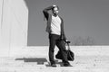 Guy in casual wear stand on stairs on blue sky, fashion. Man with bag, smartphone on steps on sunny outdoor. Macho ready Royalty Free Stock Photo