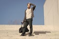 Guy in casual wear stand on stairs on blue sky, fashion. Man with bag, smartphone on steps on sunny outdoor. Macho ready Royalty Free Stock Photo