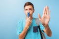 Guy closed his nose with a clothespin, bad smell, on a light blue background Royalty Free Stock Photo