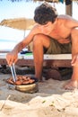 Guy Cooks Chicken Wings on Barbecue on Beach Royalty Free Stock Photo