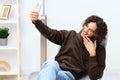 guy with curly hair sitting on a chair with a phone communication interior light background