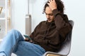 guy with curly hair sitting on a chair with a phone isolated background