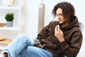 guy with curly hair sitting on a chair with a phone background