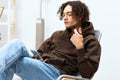 guy with curly hair sitting on a chair with a phone technologies