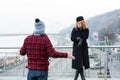 Guy delayed to date. Woman shows to watches on arm. Man spread his arms. Delayed dated on bridge.