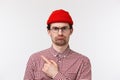 Guy disapprove boring party, express dislike. Skeptical cute caucasian male in red beanie and glasses, sulking frowning Royalty Free Stock Photo