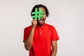 Guy with dreadlocks wearing red casual style T-shirt, covering face with social media hashtag symbol, recommending to follow