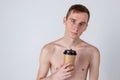 Naked handsome guy drink from coffee or tea cup. Morning refreshment and drink