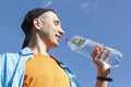 Guy drinking water from a bottle against a blue sky Royalty Free Stock Photo