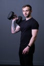 A guy with dumbbells in a black T-shirt muscular man background holding, for aged headphones in male and workout health