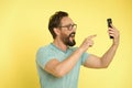 Guy eyeglasses cheerful pointing at smartphone. Man happy user interact application for smartphone. Guy bearded interact