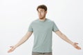 Guy feeling confused after loosing wallet. Portrait of questioned timid attractive man in t-shirt, spreading palms and