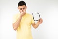 Guy feels pain in his eyes removing his glasses for vision on a white background Royalty Free Stock Photo