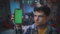 A guy in a festive hat shows a smartphone with a green screen. Close up of a guy with a smartphone on a blurred Royalty Free Stock Photo