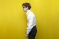 guy in festive outfit with bad posture on yellow isolated background, nerd student hunchbacked in shirt Royalty Free Stock Photo
