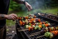 guy flipping smoked vegetables on a grill with skewers Royalty Free Stock Photo