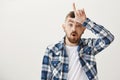 Guy gave into temptetion to mock sister. Portrait of good-looking confident young man in blue plain shirt and ear Royalty Free Stock Photo