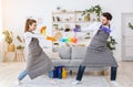 Guy and girl in aprons have fun, fight with spray, brush and broom.