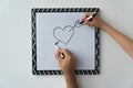 A guy and a girl draw a heart with markers on a white board. A mask and a female hand against a white board with a symbol of love Royalty Free Stock Photo