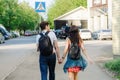 Guy with girl go holding hands along road in city on summer sunny day, back view
