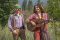 Guy and a girl in hippie style with a guitar in a forest clearing Royalty Free Stock Photo