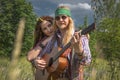 Guy and a girl in hippie style with a guitar in a forest clearing on a sunny day. Royalty Free Stock Photo