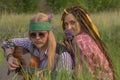 Guy and a girl in hippie style with a guitar are sitting in the grass on a forest glade. Royalty Free Stock Photo