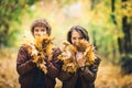 Guy and girl hold in their hands lot of autumn maple leaves and close their faces.