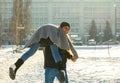 The guy and the girl indulge in the winter, he holds her on his shoulders and turns. A loving couple is playing outside Royalty Free Stock Photo