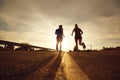 A guy and a girl jog along the road at sunset in nature. Royalty Free Stock Photo