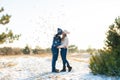 The guy with the girl kiss in the winter in the woods against the background of falling candy. Romantic winter atmosphere