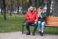 A guy and a girl are resting on a bench in an autumn park. A loving couple in jackets sits on a bench in the main park Royalty Free Stock Photo