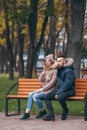 A guy and a girl are resting on a bench in an autumn park. A loving couple in jackets sits on a bench in the main park Royalty Free Stock Photo