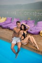 Guy and girl resting near swimming pool on background of beautiful views of forests, hills, river with a haze over it