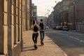 a guy and a girl ride skateboards in a large city on a sunny summer evening