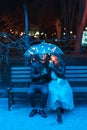 Guy and girl sitting on a bench under an umbrella Royalty Free Stock Photo