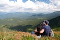 A guy and a girl are sitting on a mountain meadow, with a picturesque and mysterious view of the Ukrainian Carpathian Mountains Royalty Free Stock Photo